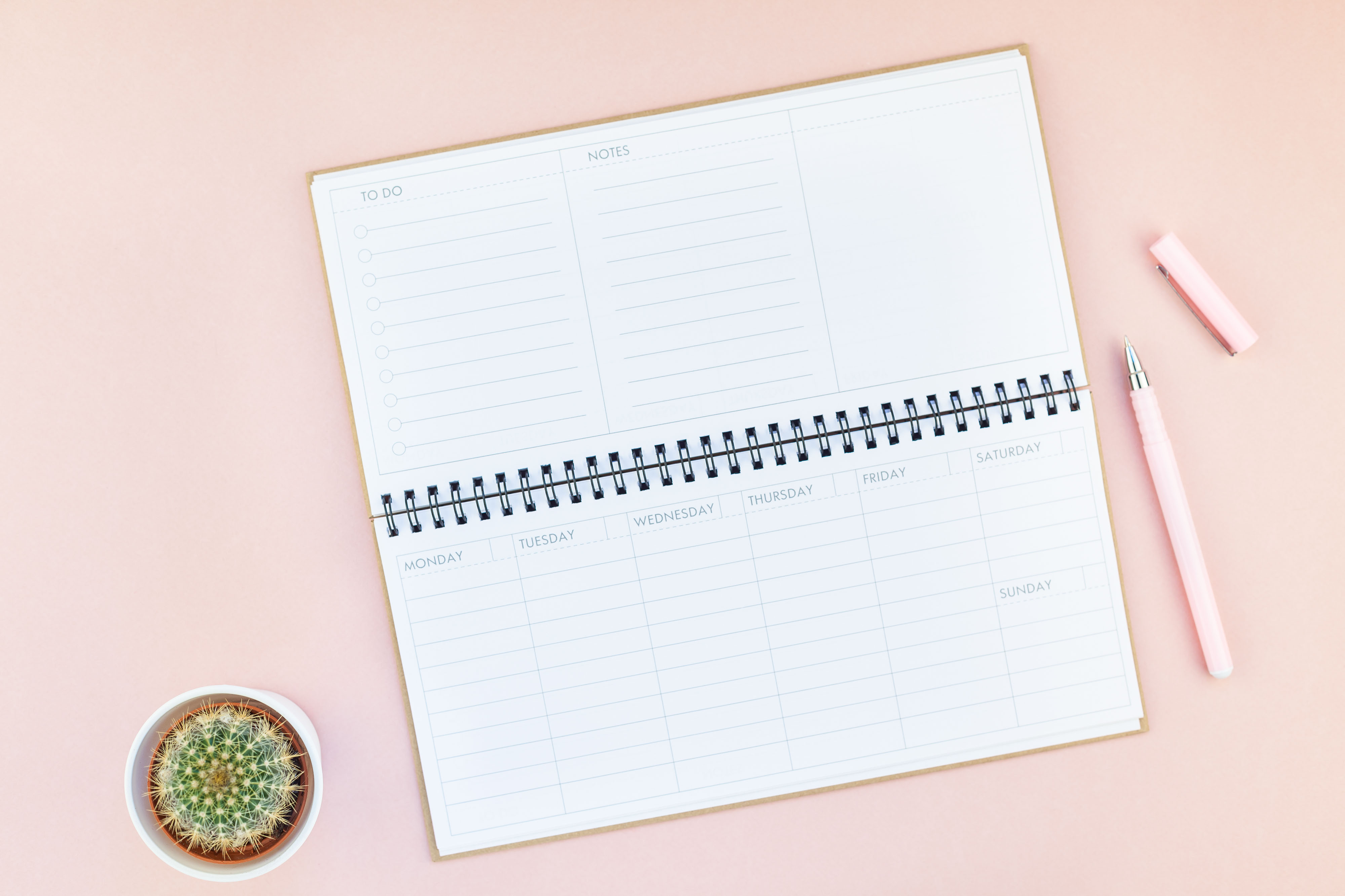 Printed weekly planner template laid on a light linen surface with a pen and succulent plant nearby